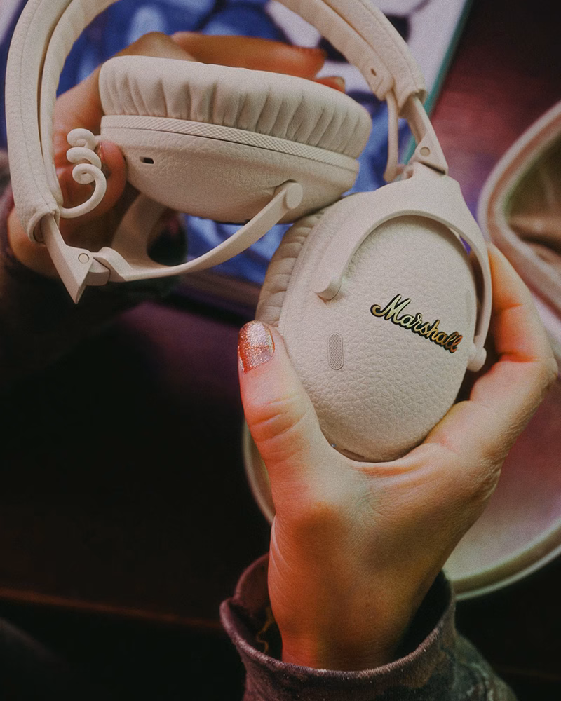 Користувач тримає навушники Marshall Monitor III ANC Cream, демонструючи їх компактність та преміальні матеріали.