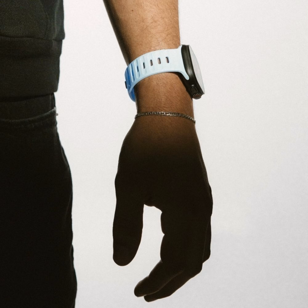 Мужская рука с Apple Watch Ultra на ремешке Nomad Icy Blue Glow, демонстрация надежной фиксации и спортивного дизайна бренда Nomad