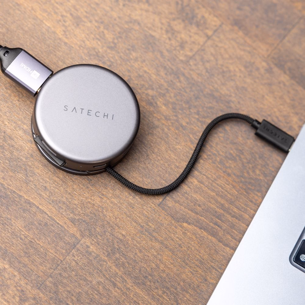 USB-C хаб Satechi на дерев'яній поверхні, підключений до MacBook через міцний плетений кабель, вихід HDMI для монітора
