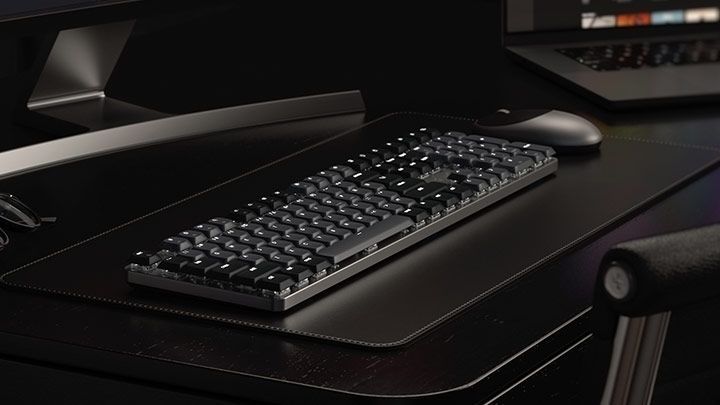Вигляд механічної клавіатури Satechi SM3 Slim з підсвіткою у темному інтер'єрі на шкіряному килимку поруч із мишкою.